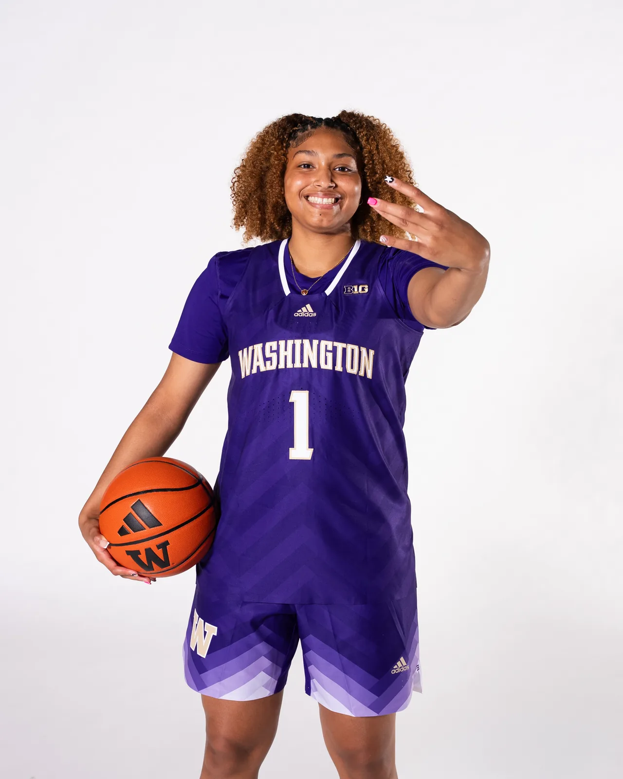 Amayah Garcia in her purple Washington number 1 jersey, holding a basketball on her hip.