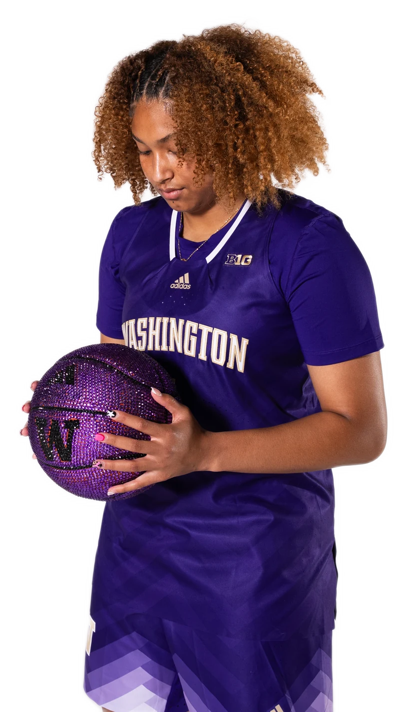 Amayah Garcia in a purple Washington jersey, cradling a crystal basketball and looking down at it.