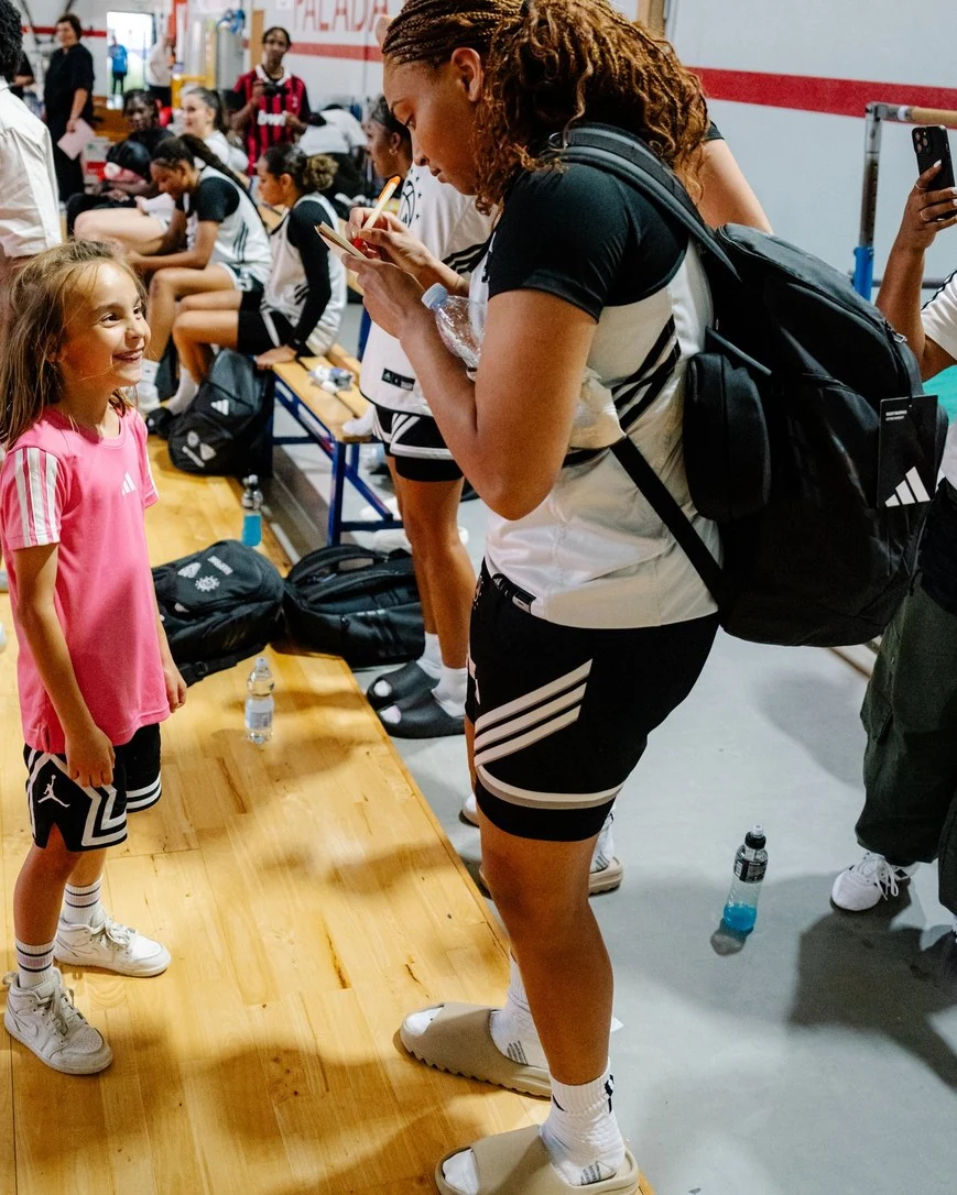 Amayah Garcia stopping to sign an autograph for a young girl courtside at the Adidas Eurocamp in Italy.