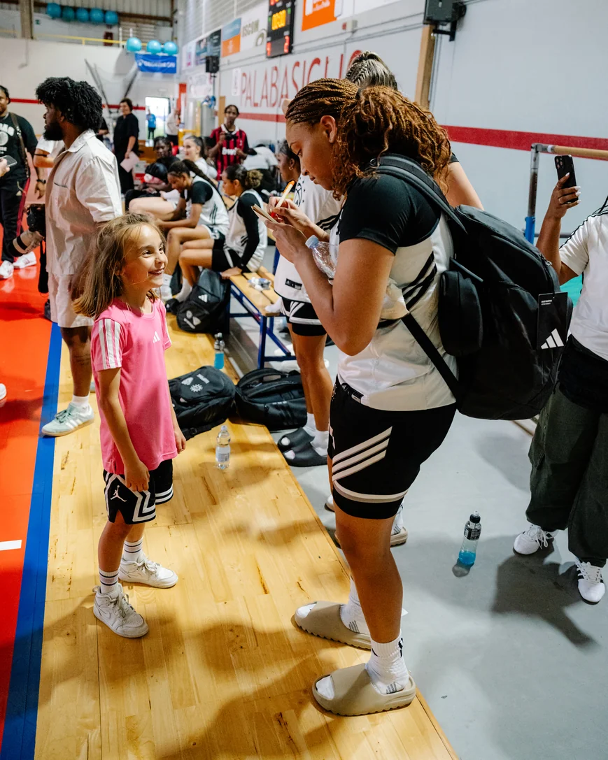 Amayah Garcia signing an autograph for a smiling young fan courtside in Italy.